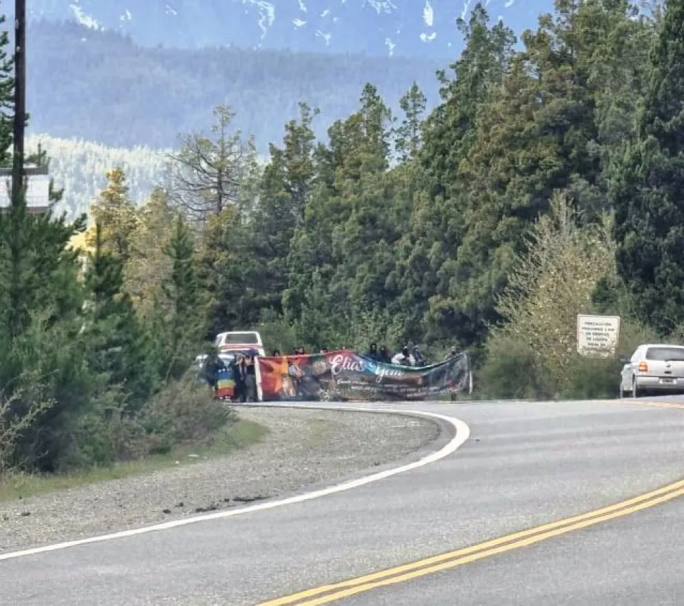 Grupo de personas con banderas mapuches marchan por ruta 40 hacia El Bolsón